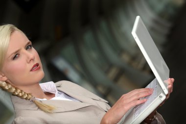 Serious woman wearing a beige suit is working on her laptop in a dark tunne clipart