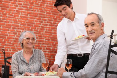 Old couple having meal in restaurant clipart