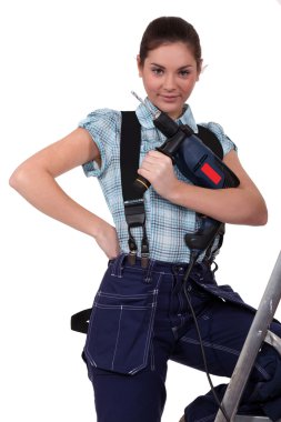 Cute teenage apprentice holding electric drill with leg resting on ladder clipart