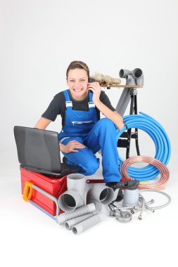 Female plumber knelt down by equipment clipart