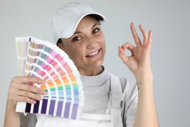 Painter giving the a-ok sign and holding a palette of colour samples clipart