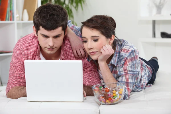 Par i sängen med laptop och godis — Stockfoto