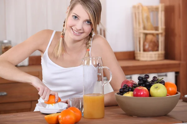 Mulher fazendo suco de laranja na cozinha — Fotografia de Stock