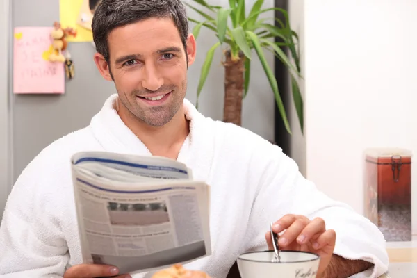 Homem lendo jornal e tomando café da manhã — Fotografia de Stock