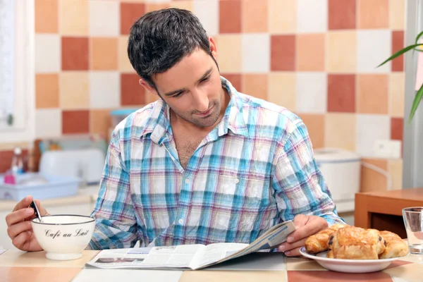 Uomo che legge il suo giornale al tavolo della colazione — Foto Stock