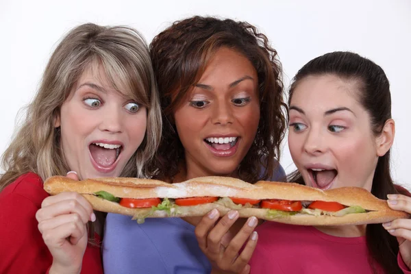 Un groupe d'amis mangeant un long sandwich — Photo