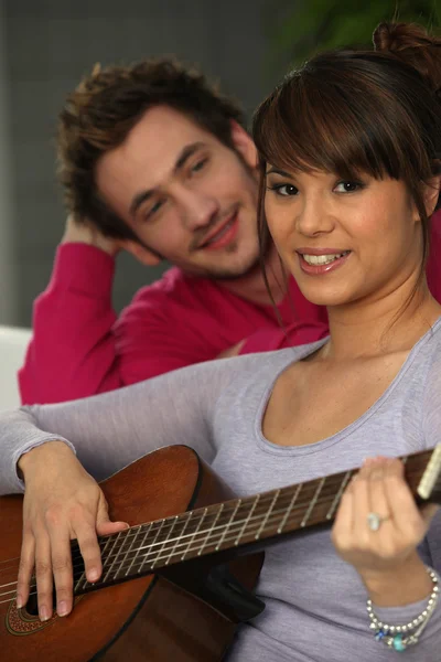 A man looking a woman playing guitar — Stock Photo, Image