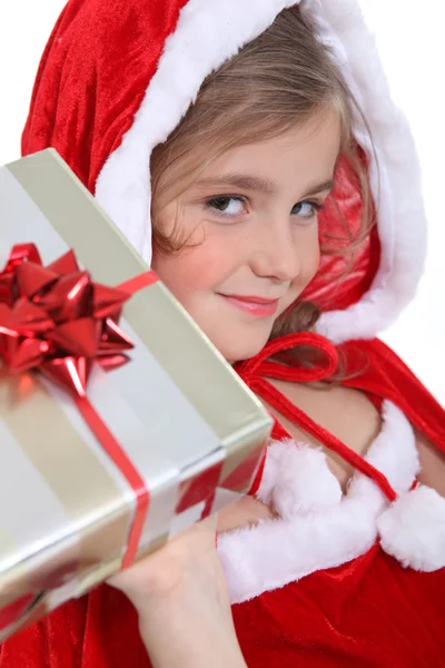 Criança glamourosa em uma roupa de Papai Noel oferecendo um presente — Fotografia de Stock