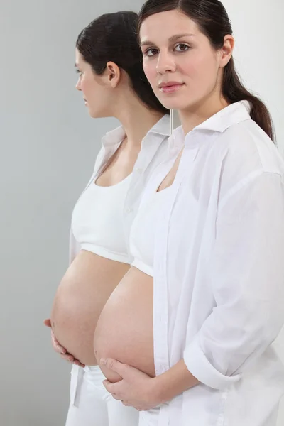 Uma mulher grávida em pé na frente de um espelho . — Fotografia de Stock