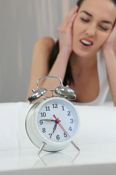 Несчастная женщина закрывает шум своего будильника — стоковое фото