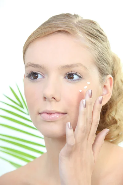 Mujer rubia joven aplicando crema anti-arrugas —  Fotos de Stock