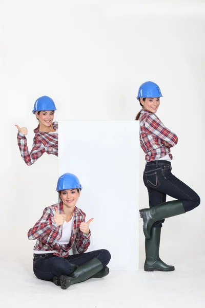 Female builder with a board left blank for your message — Stock Photo, Image