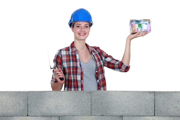 Kvinna i murarkläder med en husformad spargris — Stockfoto