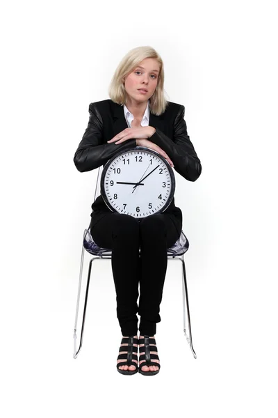 Žena sedící s hodinami na kolenou — Stock fotografie
