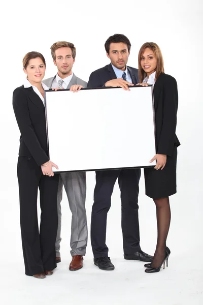 Quatro jovens executivos segurando um quadro emoldurado deixaram em branco para sua imagem — Fotografia de Stock