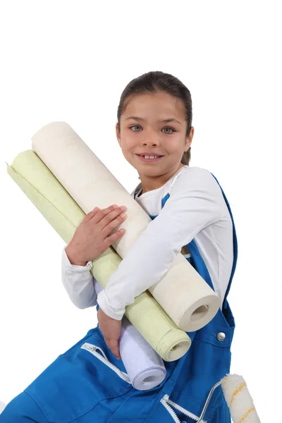Little girl holding wallpaper rolls — Stockfoto