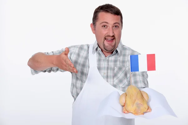 Man i en vit förkläde erbjuder en hela franska kyckling — Stockfoto