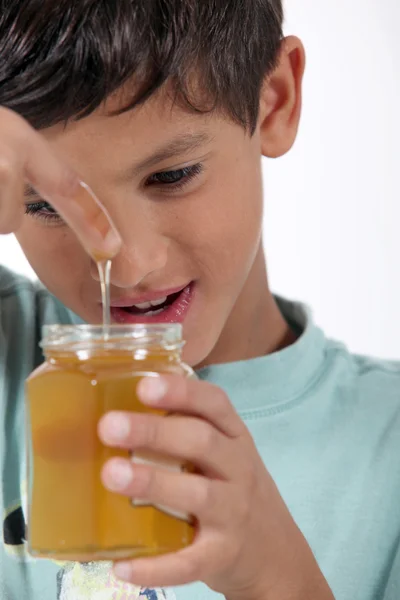 Kleiner Junge hält Glas mit Honig — Stockfoto