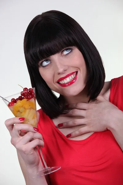 Žena v červeném jíst ovocný salát — Stock fotografie