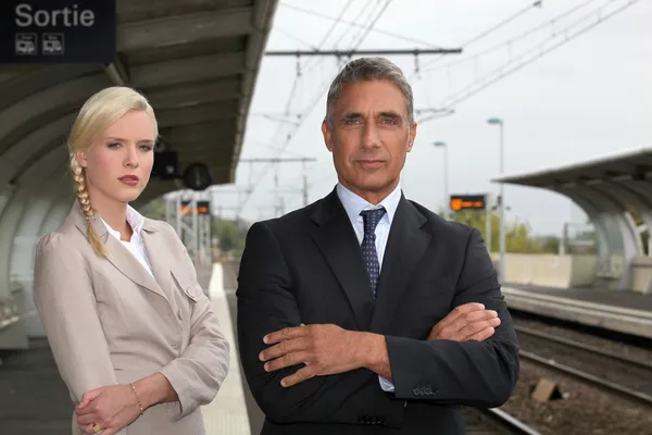 En blond kvinna och en mogen man väl klädd i en järnvägsstation — Stockfoto