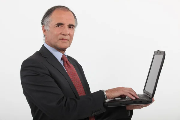 Een volwassen zakenman met een laptop. — Stockfoto