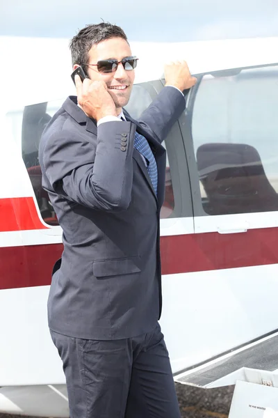 Businessman joyful leaning on an airplane — Stock Photo, Image