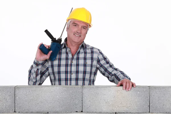 Builder stod vid väggen med borrmaskin — Stockfoto