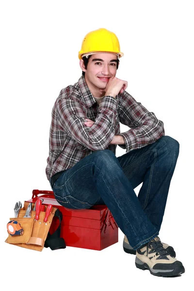 Jovem construtor sentado na caixa de ferramentas — Fotografia de Stock