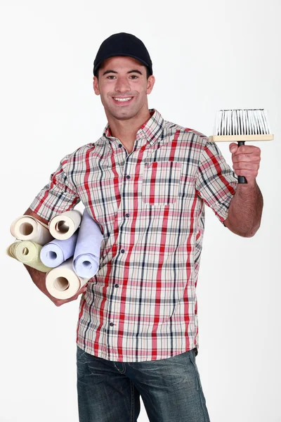 Retrato de do-it-yourselfer llevando rollos de papel pintado y cepillo — Foto de Stock