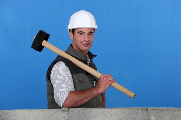 Handelaar holding een hamer en permanent achter een lage muur — Stockfoto