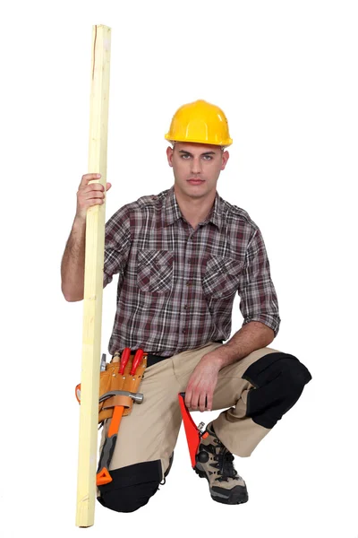 Carpenter kneeling with plank of wood — Stock Photo, Image