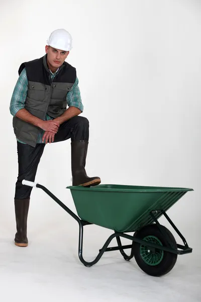 Tradesman with his foot propped on a wheelbarrow — Stock Photo, Image