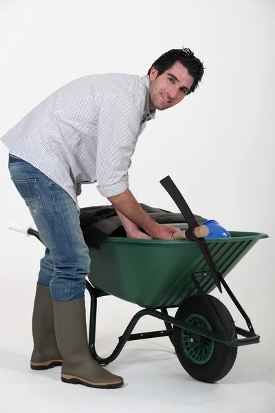 Man placing his personal belongings in a wheelbarrow — Stock Photo, Image