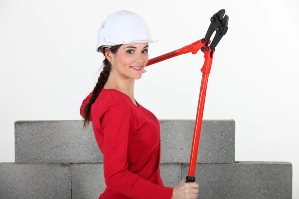 Mulher segurando cortadores de parafuso por parede inacabada — Fotografia de Stock