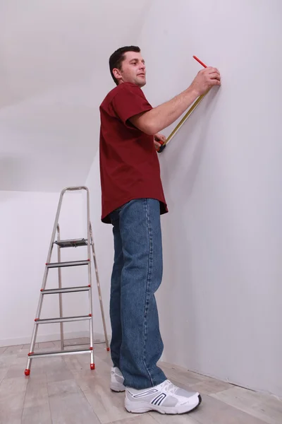 Человек измеряет стену — стоковое фото
