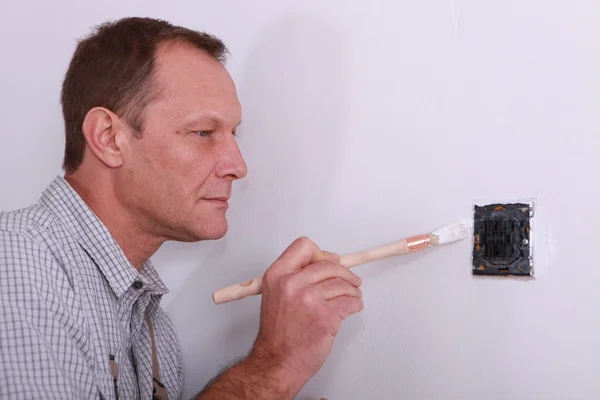 Homem pintando em torno de um interruptor de luz — Fotografia de Stock