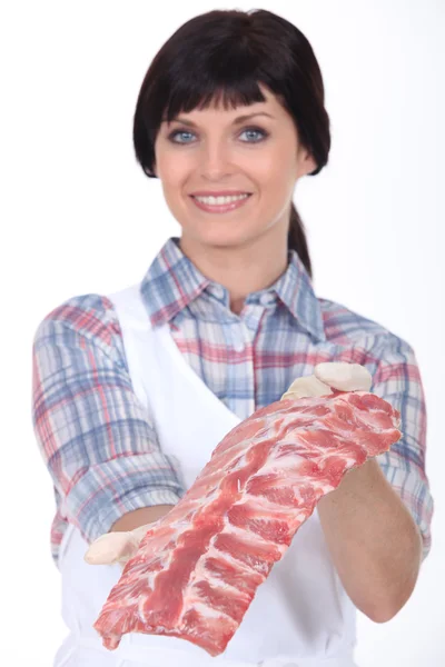 Vrouwelijke slager houden een rek van ribben — Stockfoto