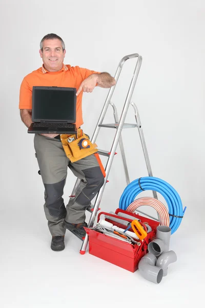 Builder with tools of the trade and a laptop computer — Stock Photo, Image