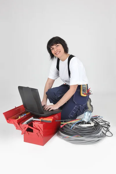 Brunett elektriker med diverse verktyg ser glad — Stockfoto