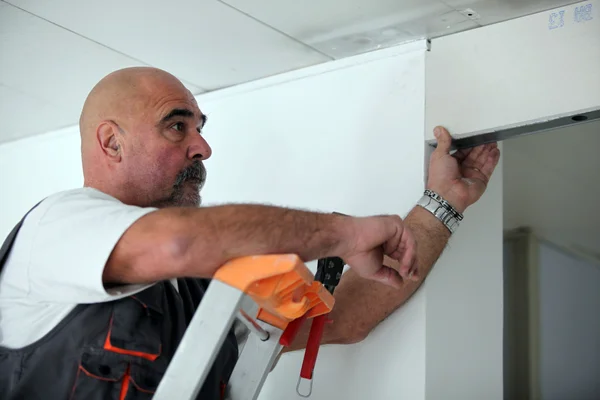Arbeiter steckt eine Tür in eine Trennwand — Stockfoto