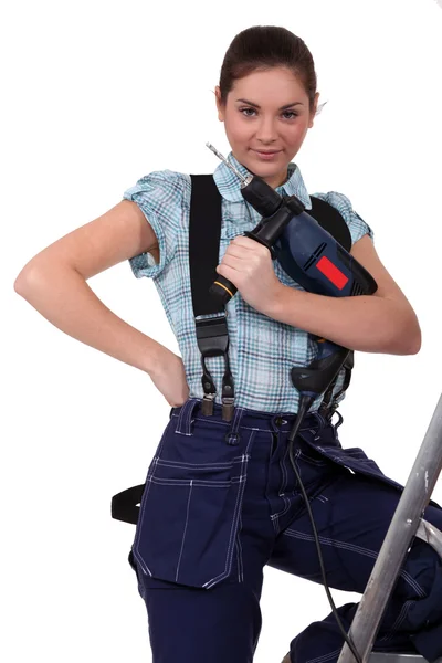 Cute teenage apprentice holding electric drill with leg resting on ladder Royalty Free Stock Images