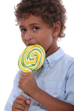 Young boy licking a lollipop clipart