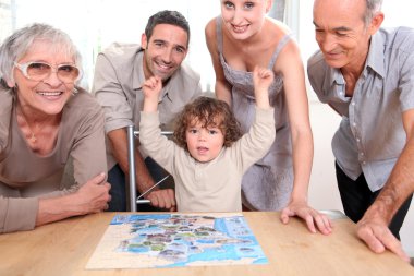 Family gathered around jigsaw puzzle clipart