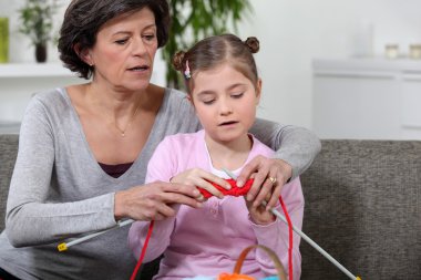 Grandmother teaching granddaughter how to knit clipart