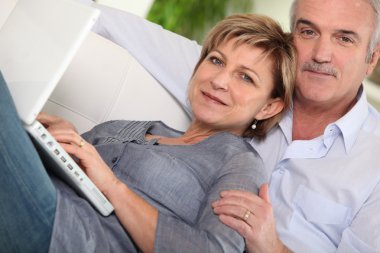 Middle-aged couple looking at their laptop clipart