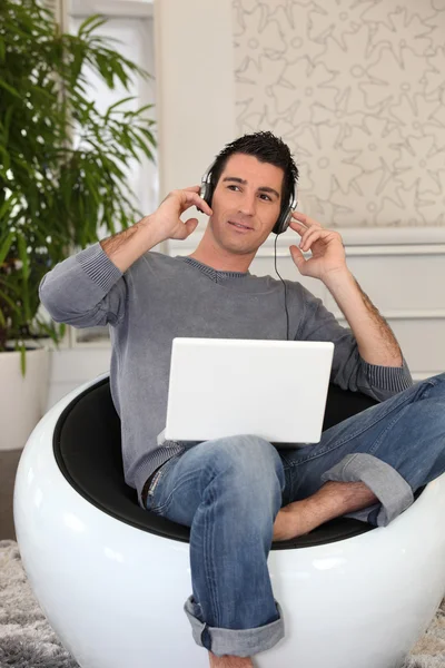 Uomo rilassato che ascolta musica sul computer portatile — Foto Stock
