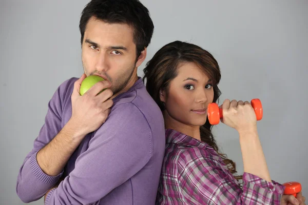 Jeune homme avec une pomme et femme avec un haltère — Photo
