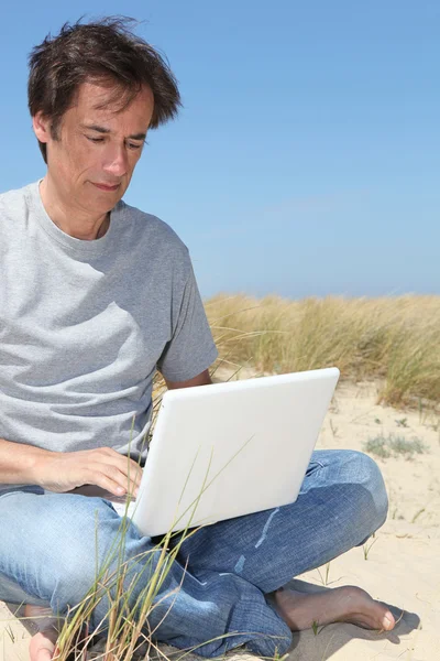 Mann auf Laptop am Meer — Stockfoto