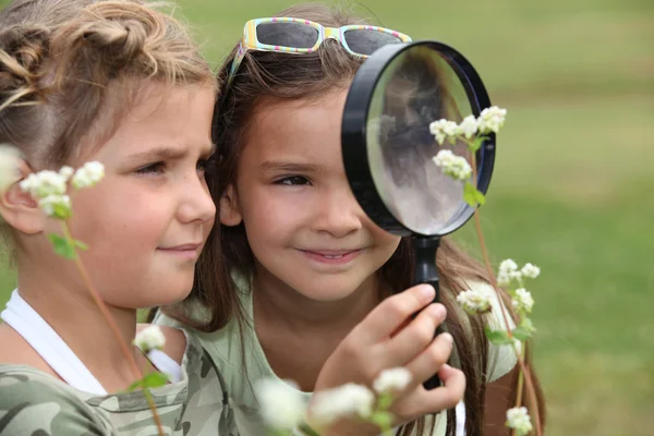 Two little girls with magnifying glasses — Stock Photo, Image