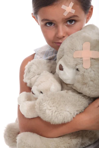 Girl and teddy with a plaster on forehead — Stock Photo, Image